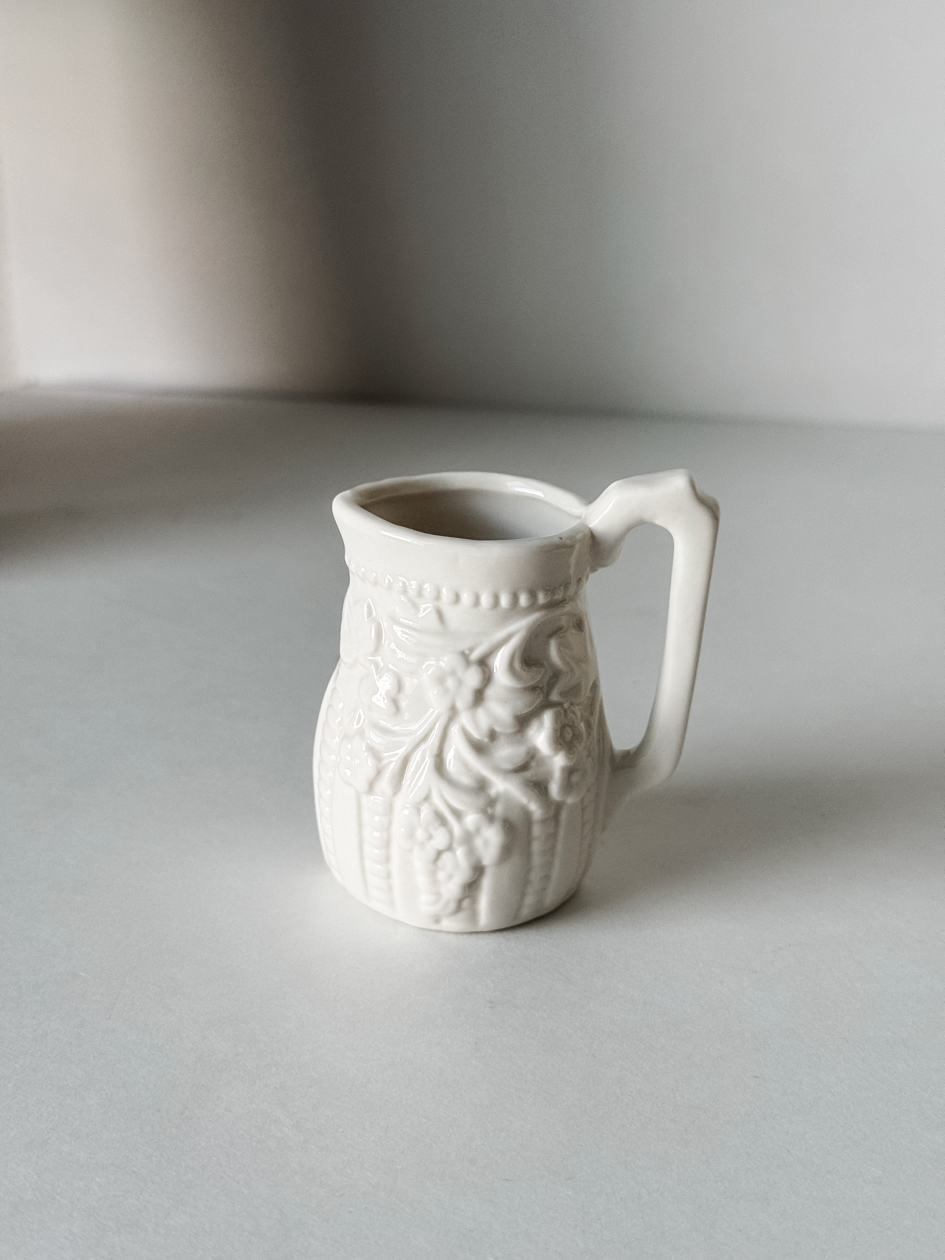 Small White Creamer With Handle And Raised Floral Details