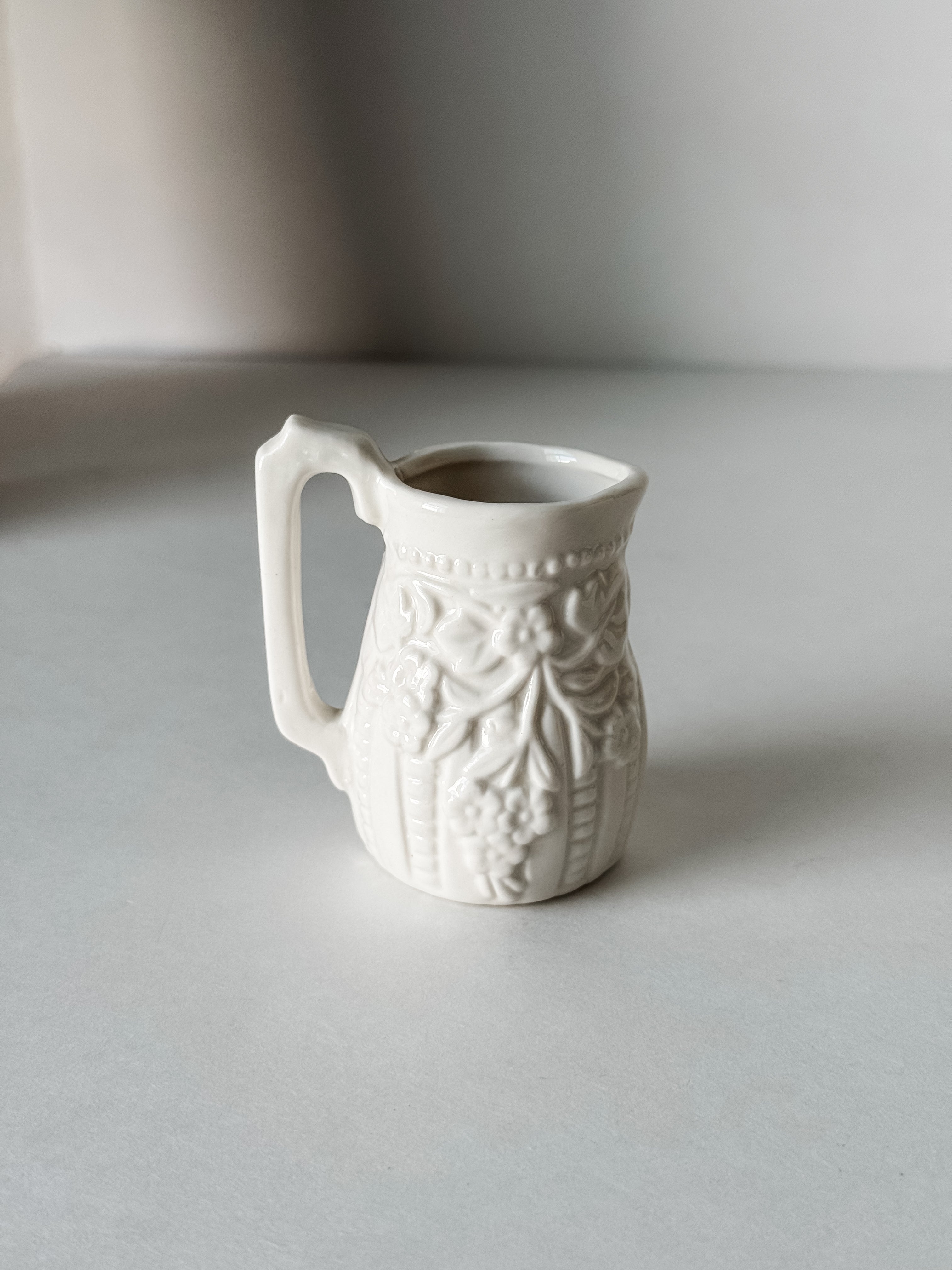 Small White Creamer With Handle And Raised Floral Details