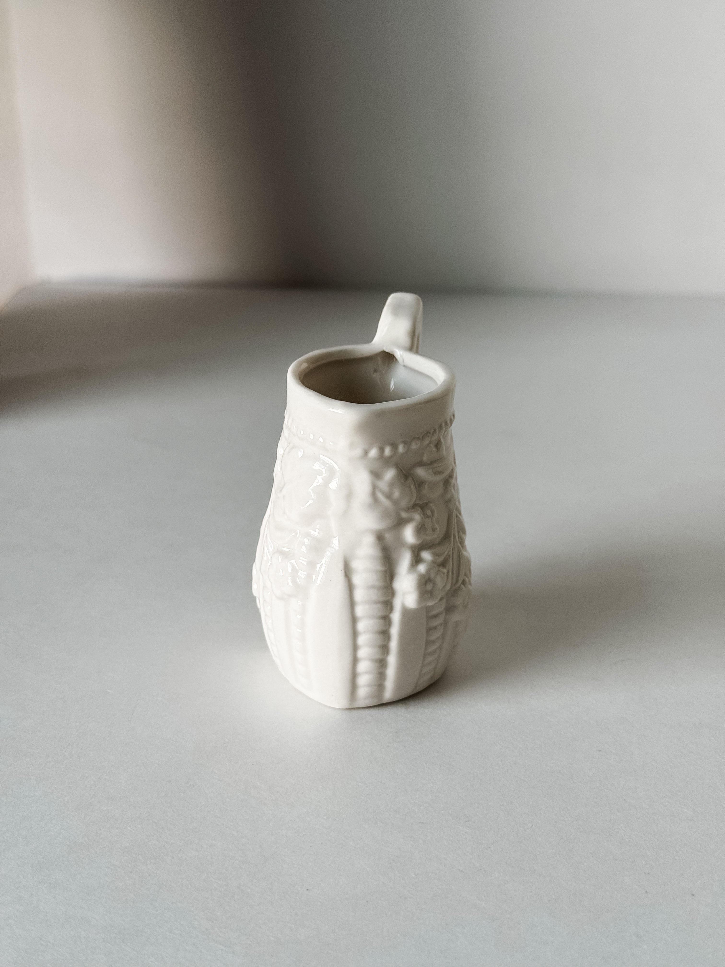 Small White Creamer With Handle And Raised Floral Details