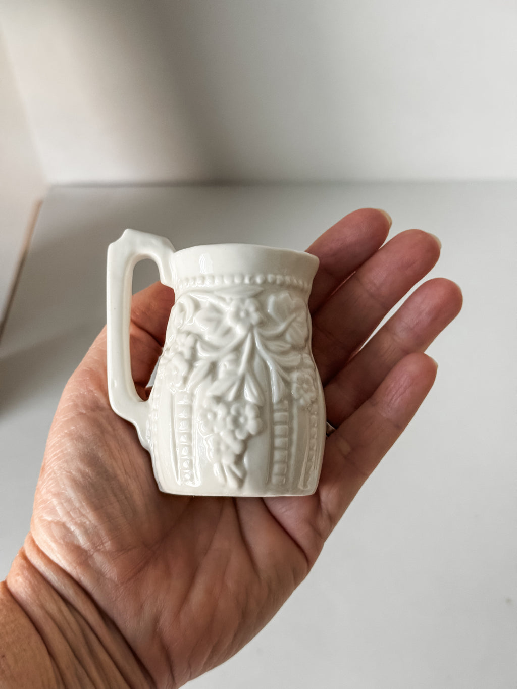 Small White Creamer With Handle And Raised Floral Details